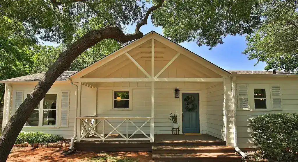 Elmwood from the street, a cream house with a gabled porch under a live oak