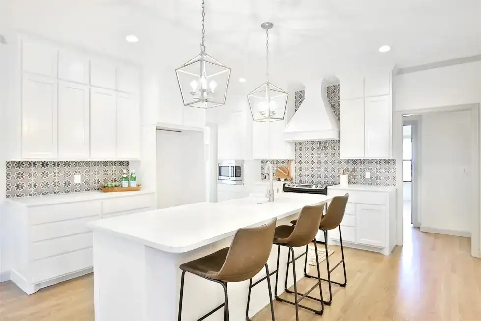Grand Avenue kitchen with a white island, pendant lanterns and patterned tile behind the range
